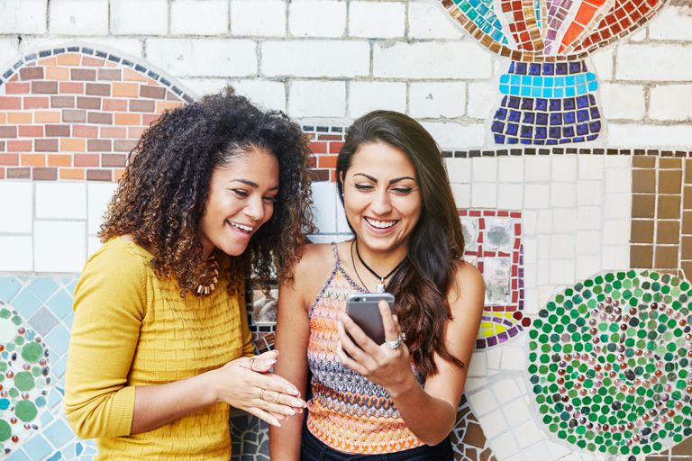 Friends with smartphone in front of mosaic wall