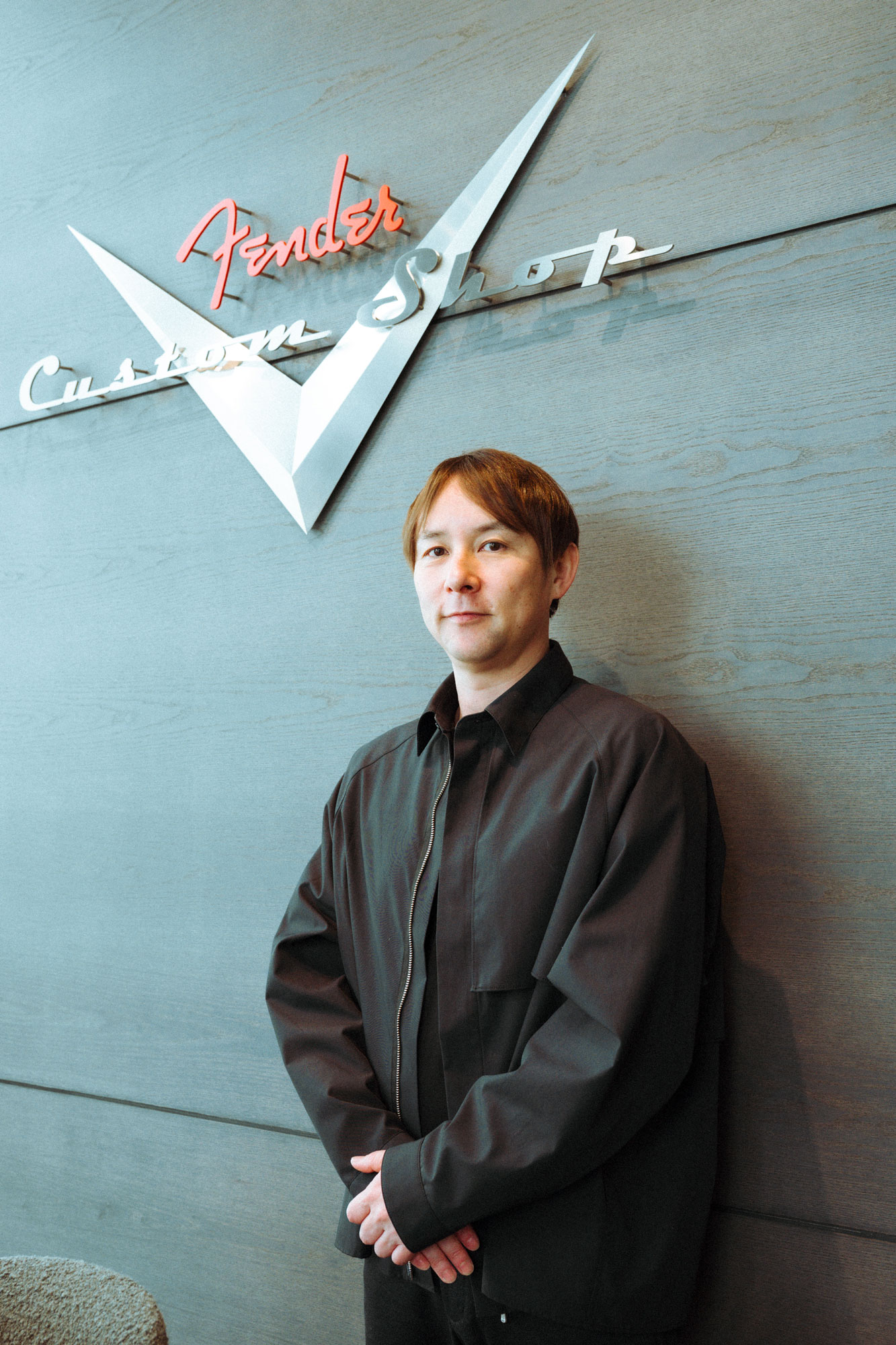 Masato Fujikawa stands in front of a Fender Custom Shop banner at Fender Flagship Tokyo.