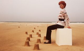 Model sat on a block in the sand on a beach