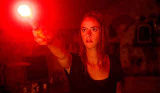 Kaya Scodelario holding out a flare in Crawl