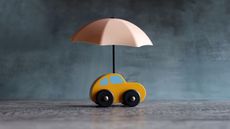 A toy car with an umbrella over it, indicating car insurance.