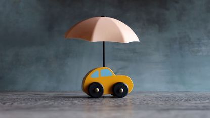 A toy car with an umbrella over it, indicating car insurance.
