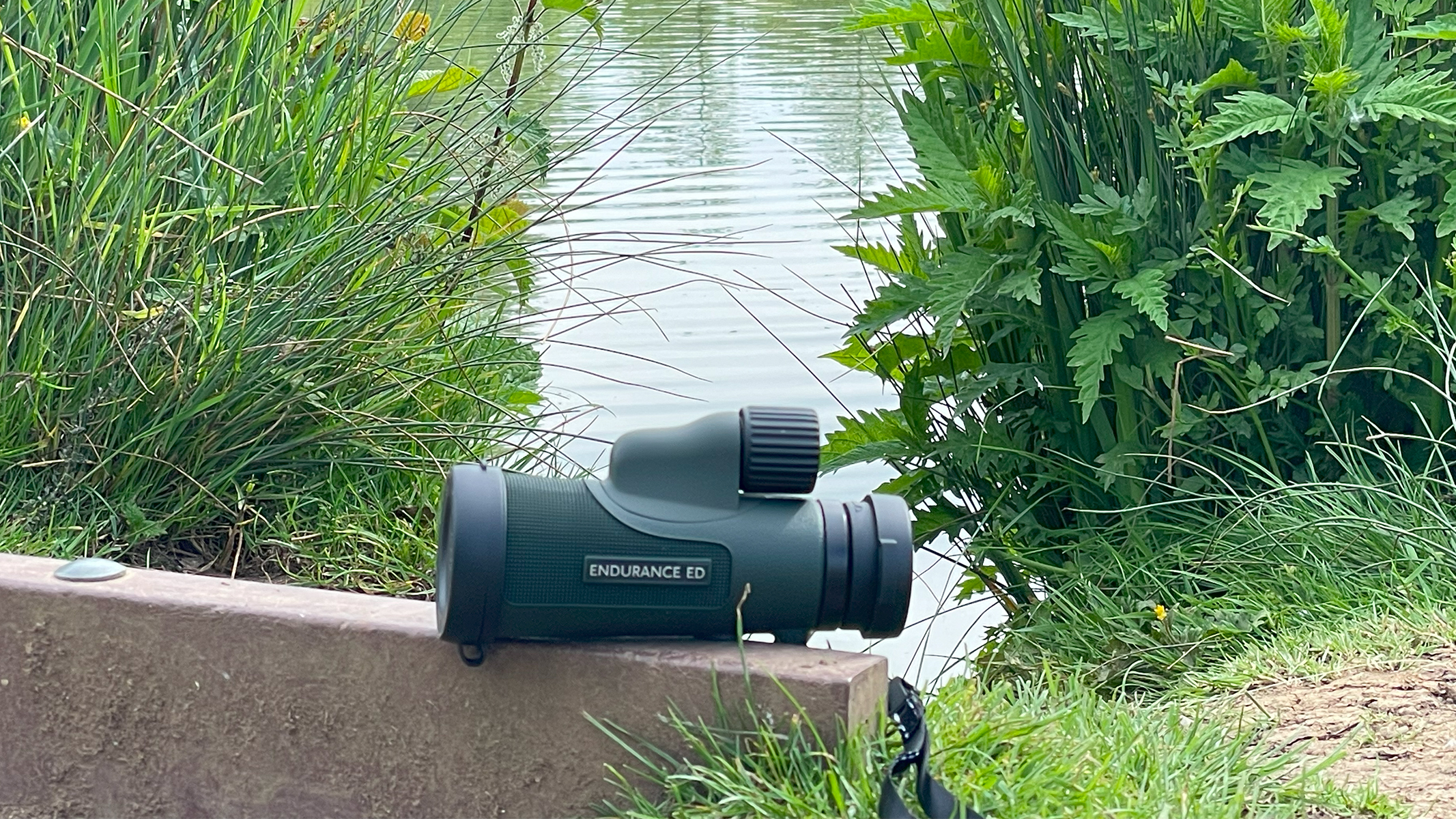 The Hawk Endurance ED 10x42 on a wall in front of a lake.