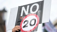 A man holds a sign during a protest against 20 mile per hour speed limits in Wales