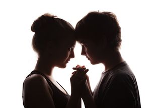 A teen couple stands facing each other