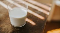 A glass of milk sitting on a wooden table