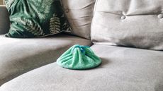 A saucepan covered with a green microfiber dish cloth on a light gray couch