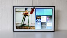 The Echo Show 21 powered on and standing up on a table