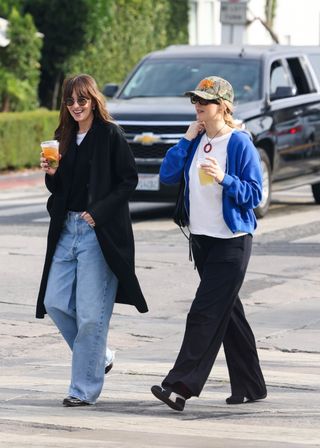 A photo of Jennifer Lawrence and Dakota Johnson wearing coordinating black and blue outfits on a walk in Los Angeles