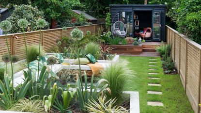 lawn in narrow garden with seating area and pathway