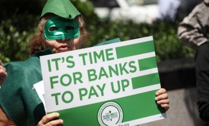 A man participates in the Robin Hood Tax Campaign protest outside JPMorgan headquarters on June 19 in New York City: While JPMorgan's profits are down 9 percent, they still amount to a startl
