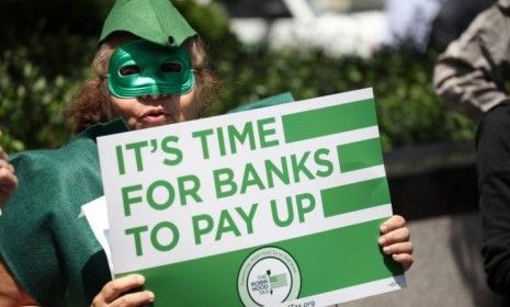 A man participates in the Robin Hood Tax Campaign protest outside JPMorgan headquarters on June 19 in New York City: While JPMorgan&amp;#039;s profits are down 9 percent, they still amount to a startl