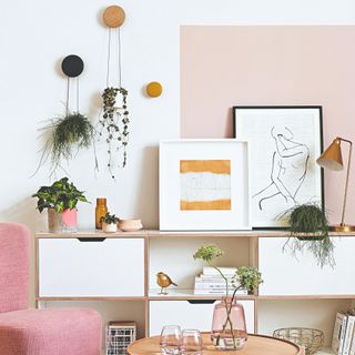 A living room with a pink chair and potted houseplants
