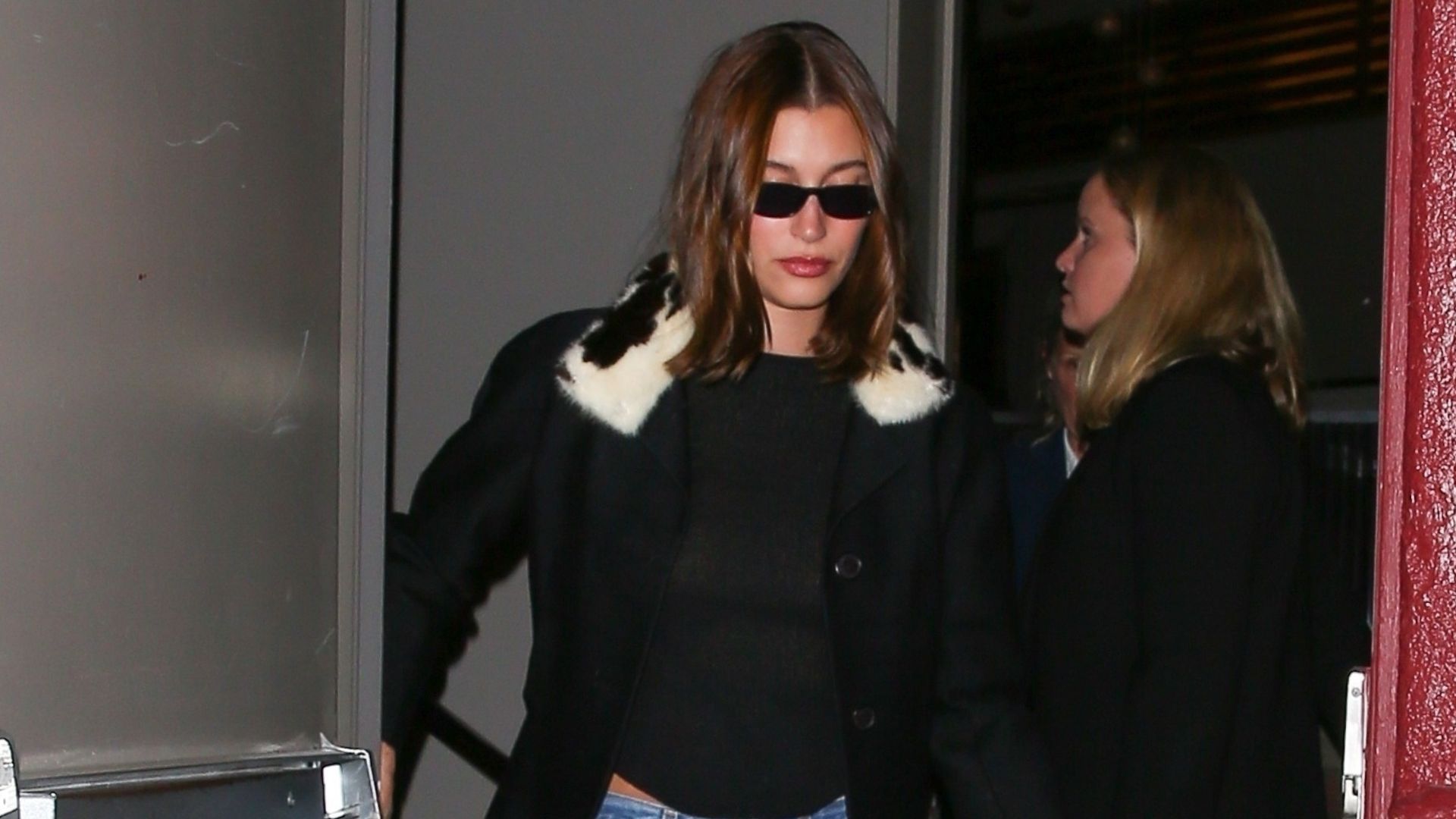 An image of Hailey Bieber wearing a cow-print faux-fur black jacket with straight-leg jeans. 