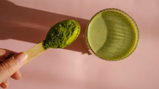 Green powder on small scoop being put into green drink