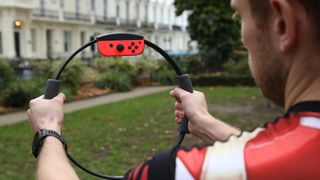Bästa Nintendo Switch-tillbehör: En man som står utomhus och +håller i en Ring Fit till Nintendo Switch.