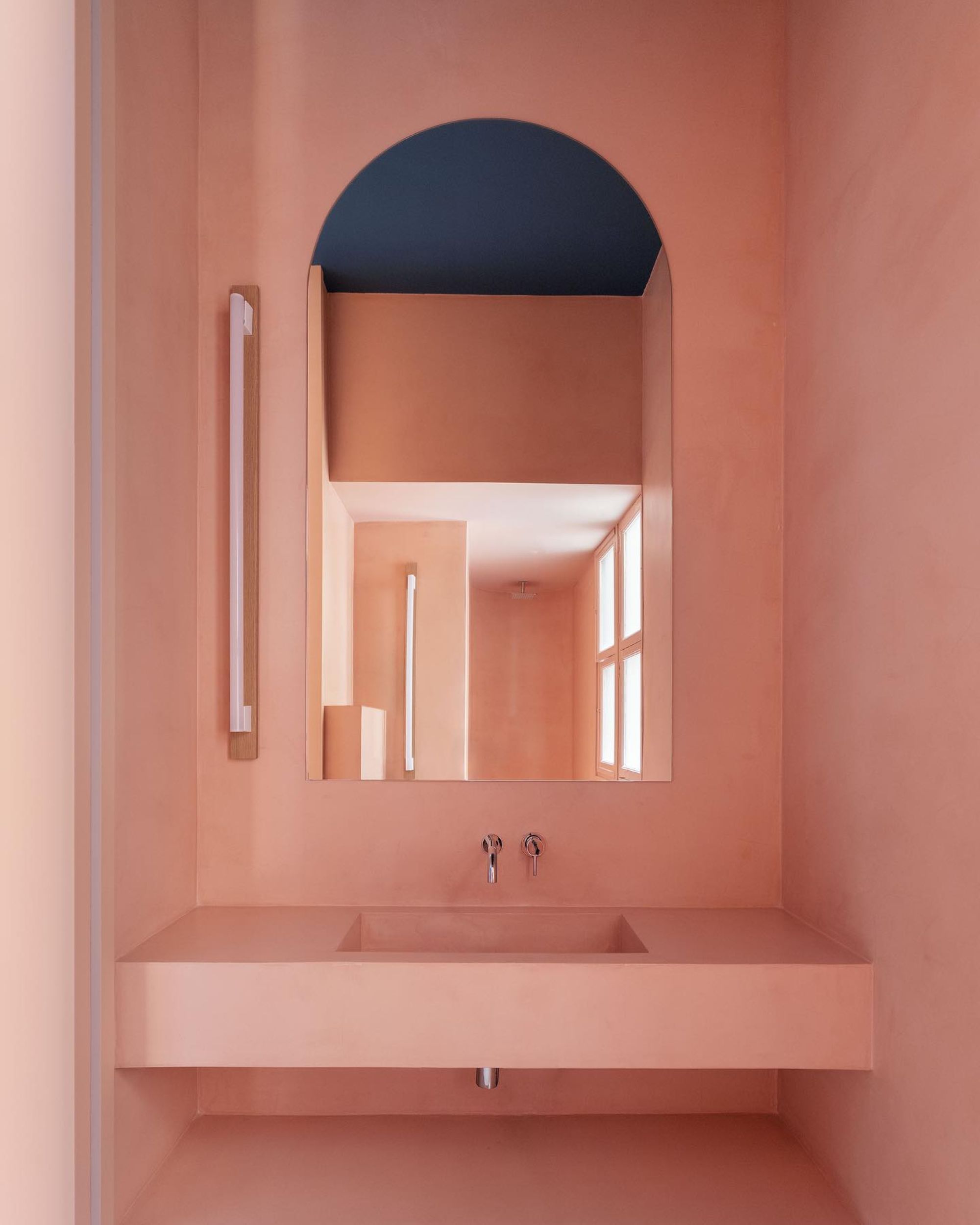 pink bathroom sink and walls with an arched mirror