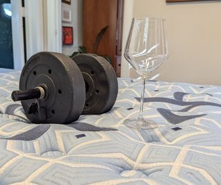 A weight beside a wine glass on the Stearns & Foster Estate Mattress.