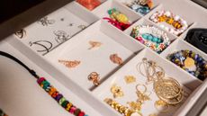 If you learn how to organize jewelry well, your drawers can look like this image too: a close-up of dainty gold and other colorful jewelry separated in a cream plush drawer divider
