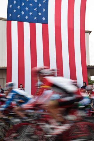 Riders speed past the American flag.