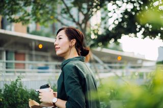 Woman drinking coffee in a park, one of the headache causes