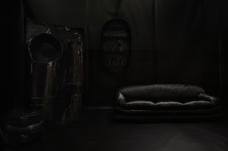 a dark room with a black sofa at an installation by faye toogood in paris