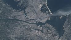 A gloomy astronaut photo of New York City showing a giant plume of smoke blowing from Manhattan during the 9/11 attacks