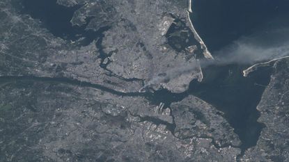 A gloomy astronaut photo of New York City showing a giant plume of smoke blowing from Manhattan during the 9/11 attacks