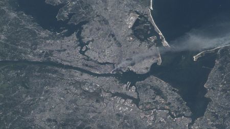 A gloomy astronaut photo of New York City showing a giant plume of smoke blowing from Manhattan during the 9/11 attacks