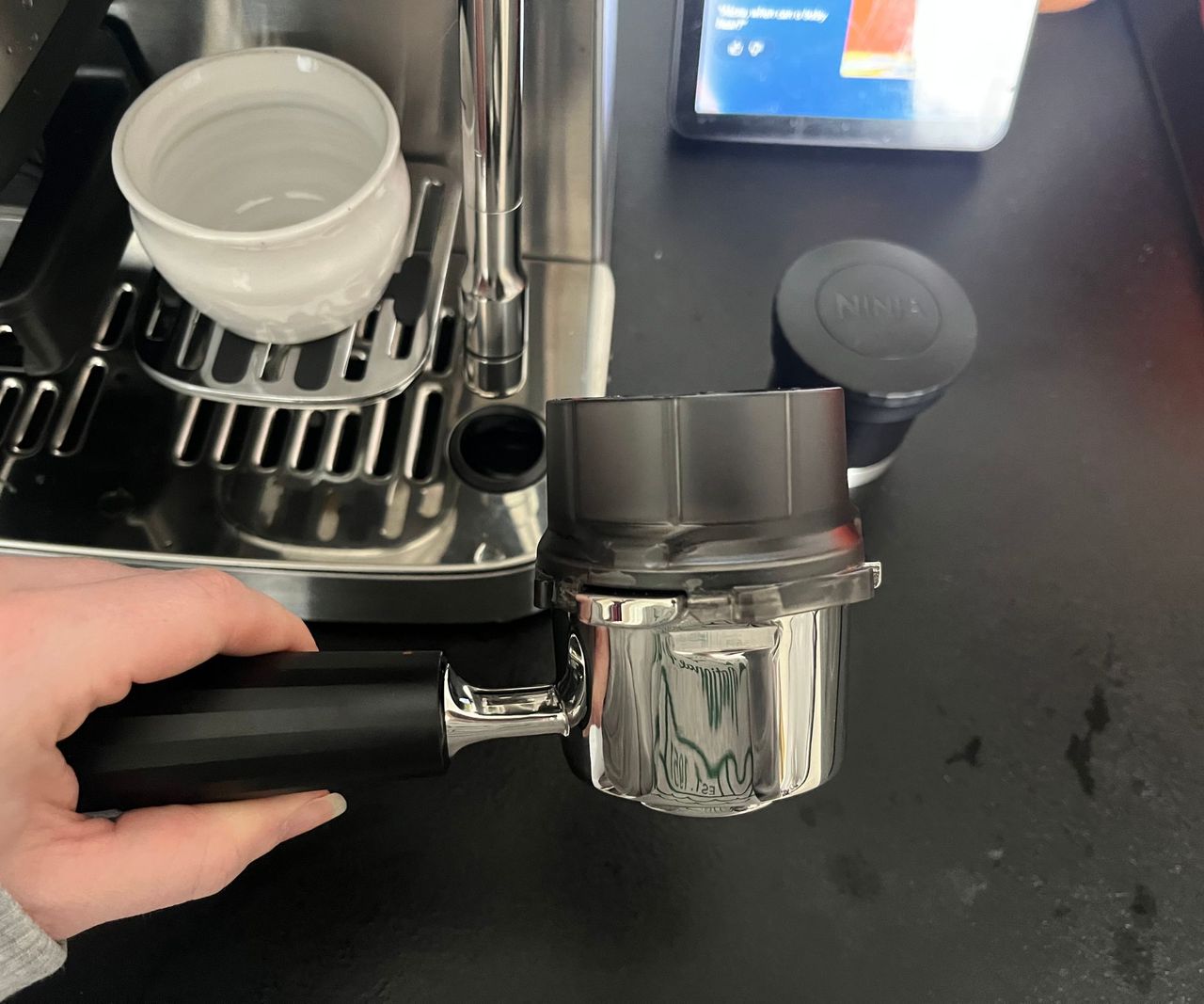 A black and silver portafilter with a black plastic funnel on top.
