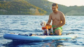 Man paddleboarding with pet dog