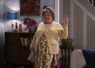 Mrs Brown in a yellow cardigan waving to the camera.