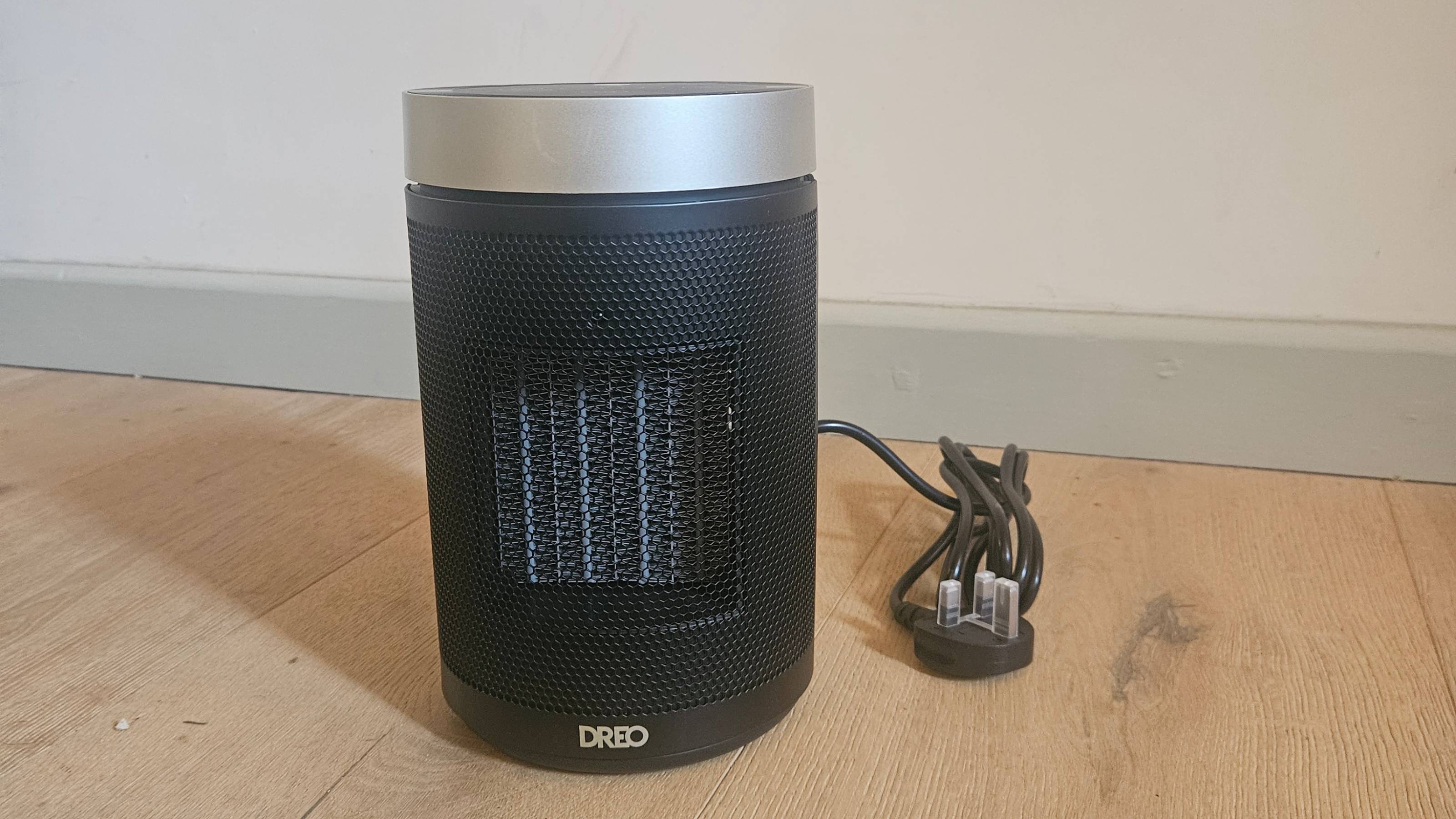 dreo black heater infront of pale blue and white wall and wooden floor