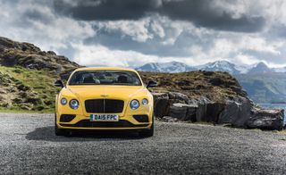Yellow Bentley motor with mountainous view in background
