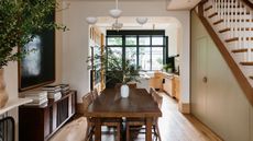 a dining room and kitchen with stairs to the left, with a door leading to a powder room. an antque table sits in the middle of the room