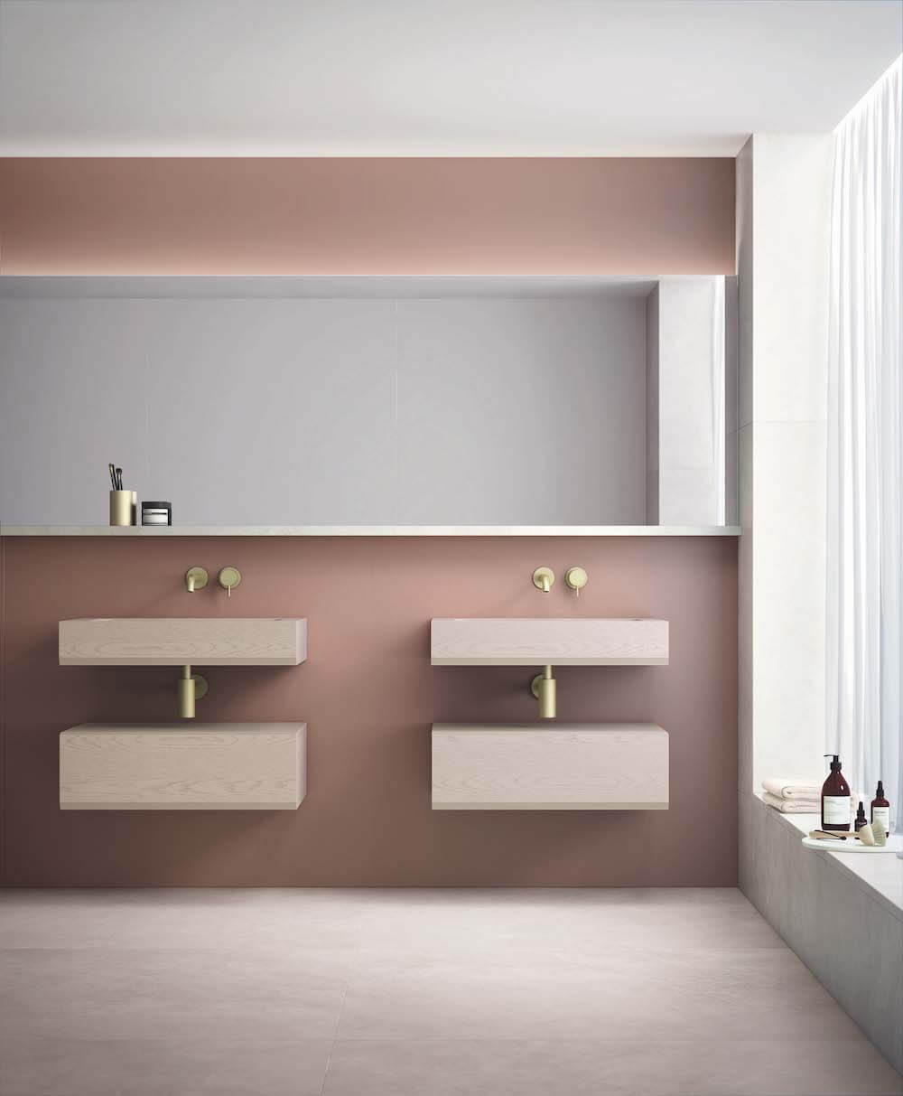 An on trend bathroom idea with pink walls, wide mirror and pair of stone sinks.