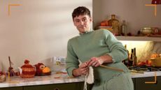 Tom Daley x Air Wick campaign focus with Tom Daley leaning on a counter with knitting