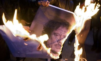 Protesters burn a photo of Moammar Gadhafi: Already, Libya's new leaders are debating how to deal with the toppled despot once he is caught.