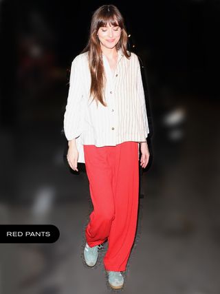 Dakota Johnson wearing a white shirt, red pants, and Adidas sneakers.