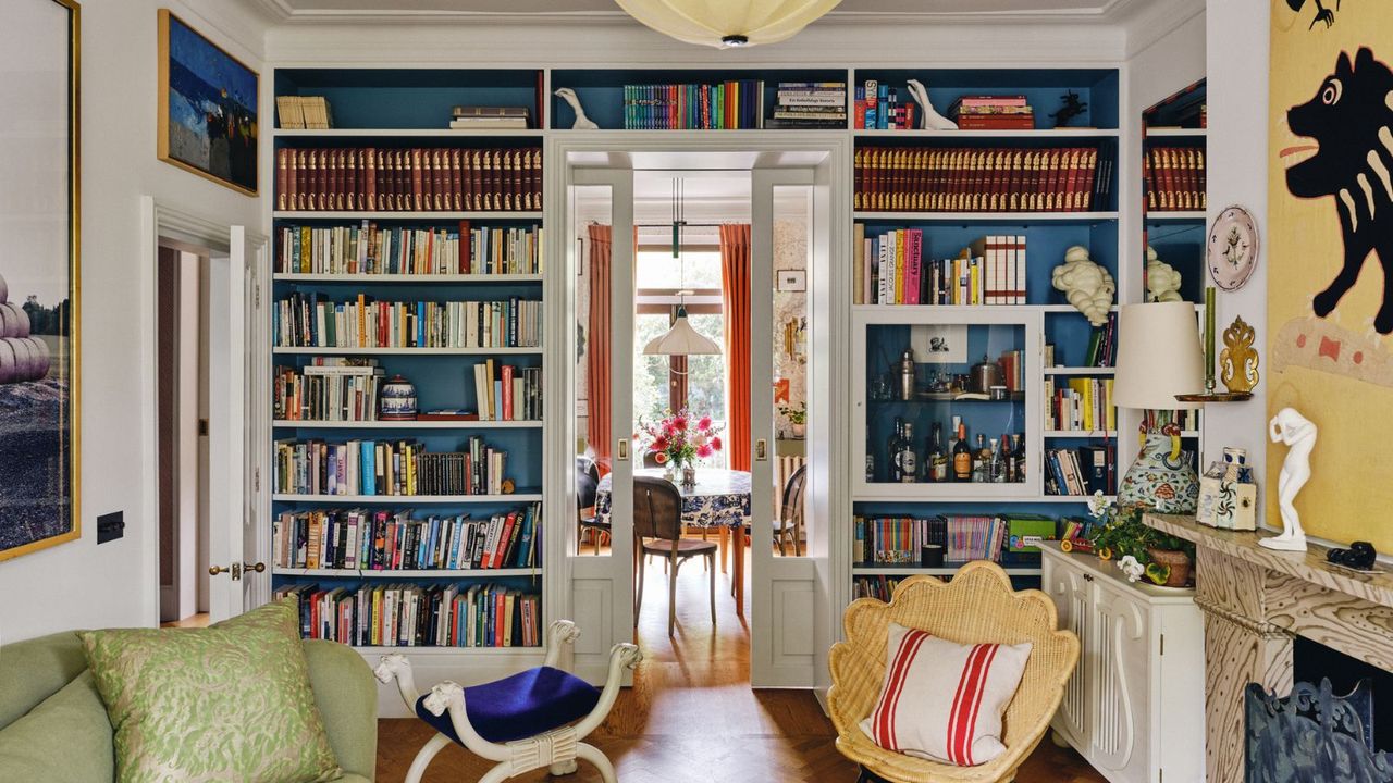 image of an eclectic living room with white walls and a large blue painted bookcase with a mix of books and vintage decor