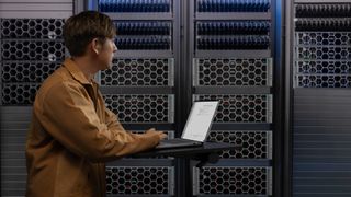 A person standing at Dell servers, using a laptop on a raised desk