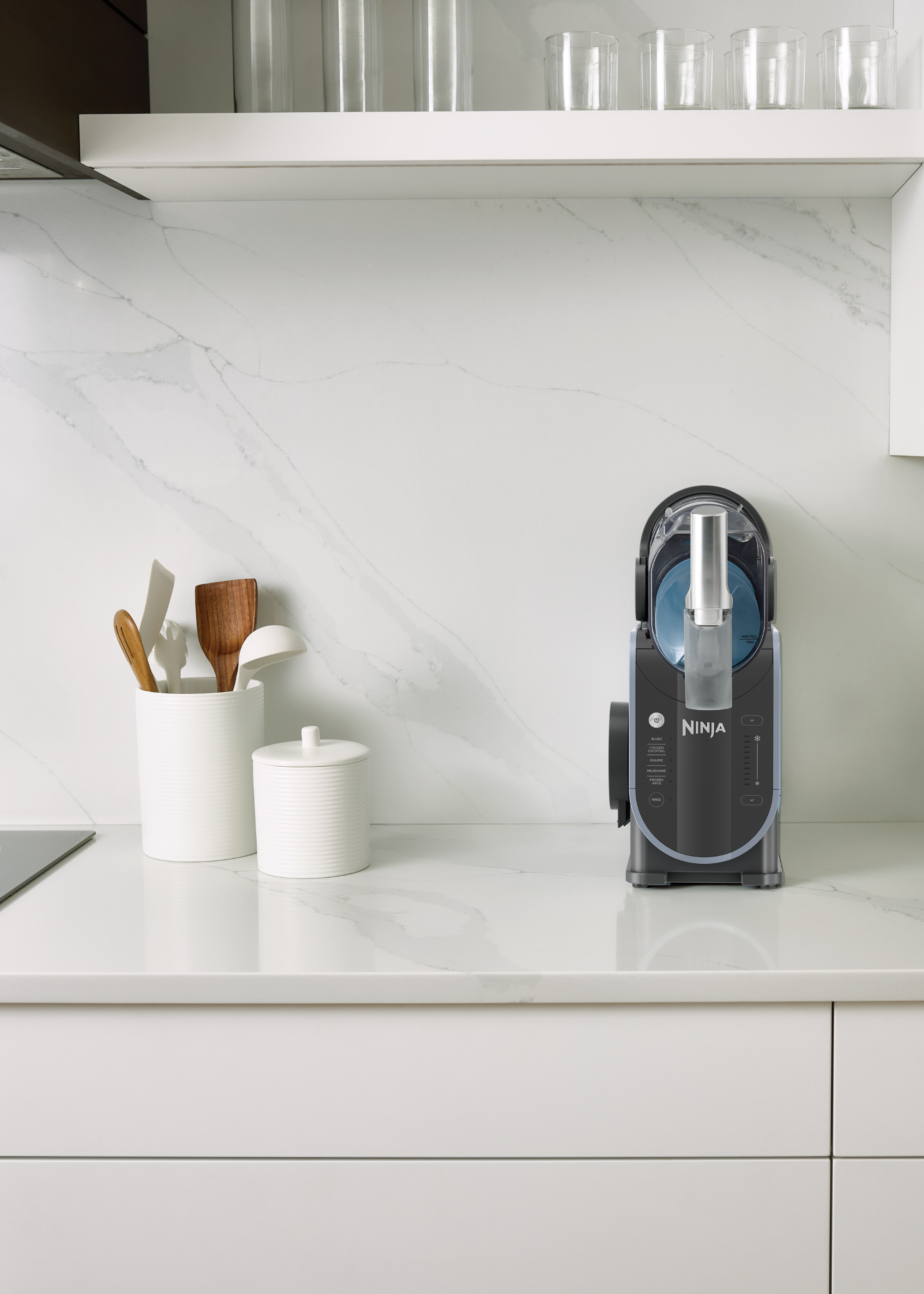 a ninja slushi in a small all white kitchen