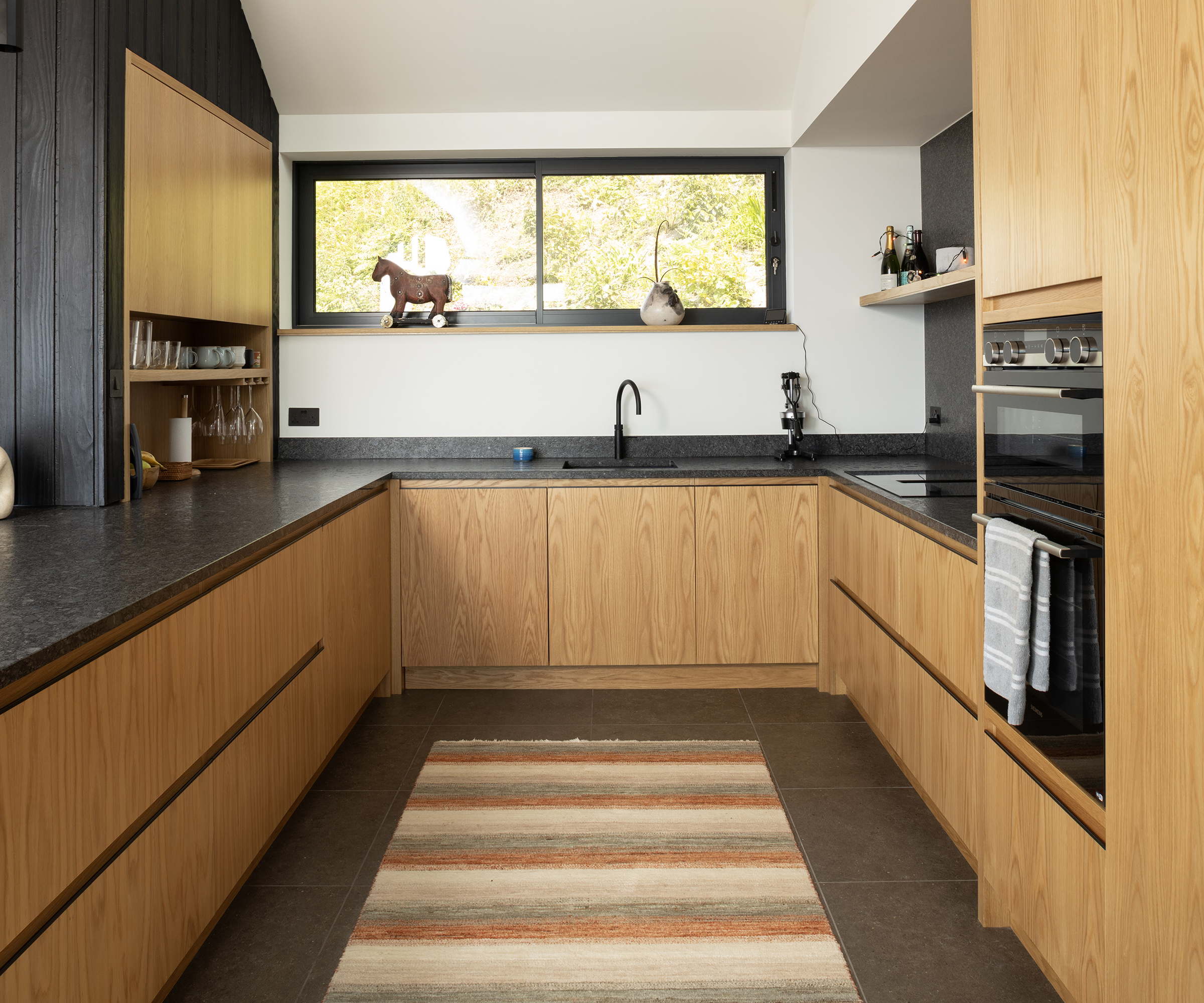 A u shaped kitchen made of wood cabinets and black surfaces