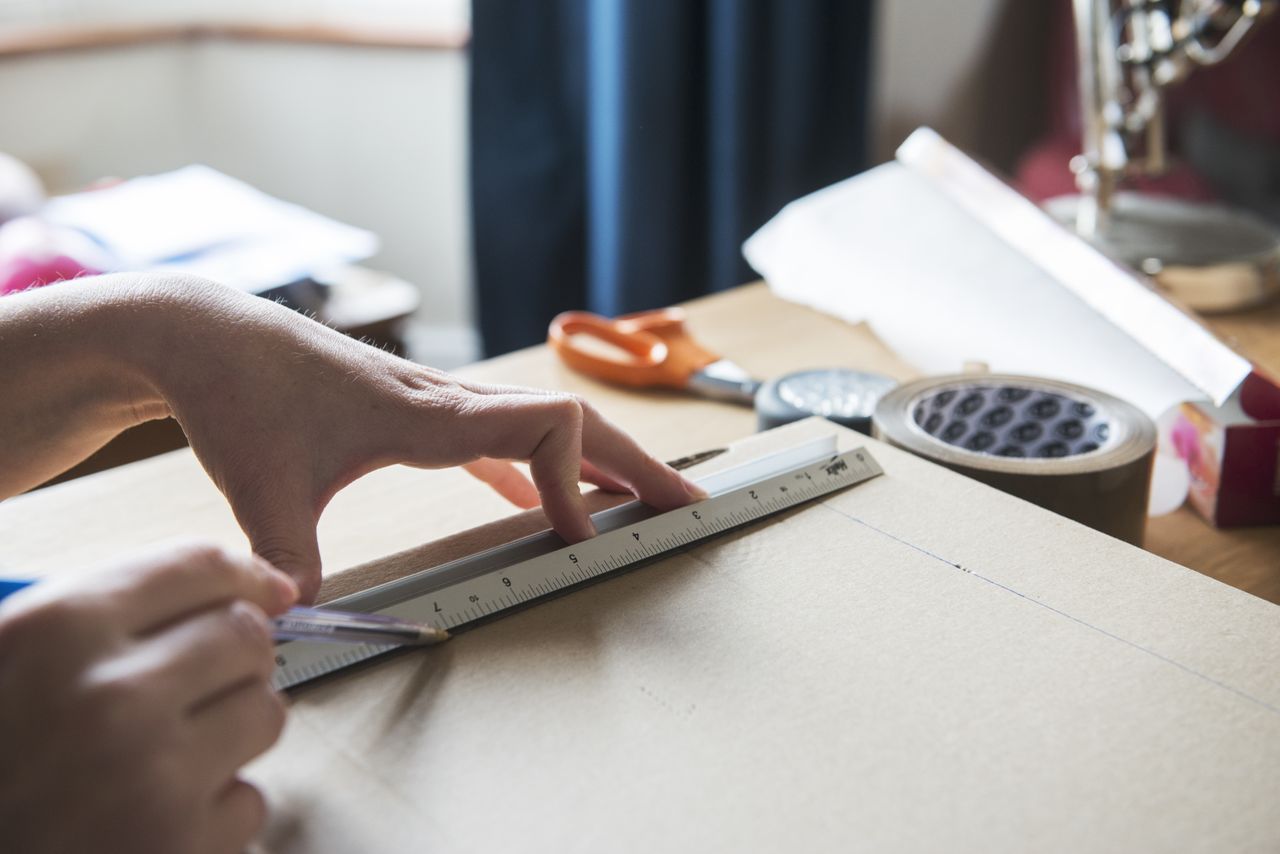 Person draws plans up with ruler