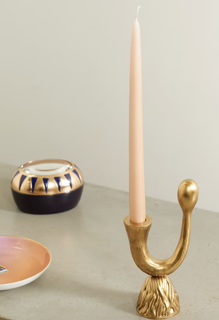 gold candlestick holding a taper candle