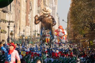 People walk under the Smokey Bear and the Ronald McDonald balloons during the 2022 Macy's Thanksgiving Day Parade.