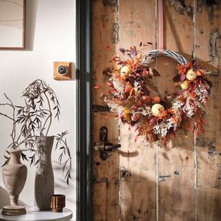 an autumnal wreath made from dried flowers and gasses and tiny pumpkins