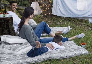 Man, woman and child sitting on The White Company Henley Outdoor Mattress on the grass