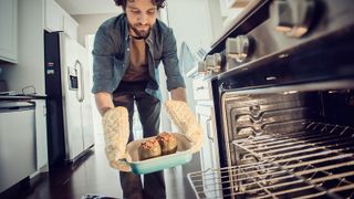 man taking food out of built-in oven