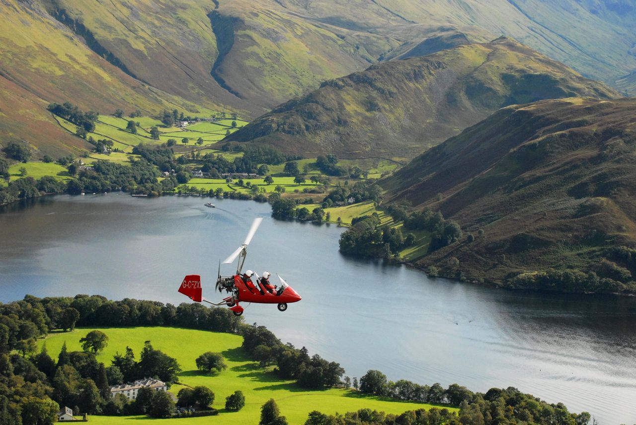 Auto gyro flying over Ullswater in the Lake District.